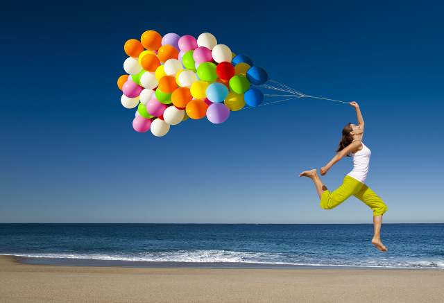 ribose energizes beautiful athletic girl with colorful balloons jumping on the beach